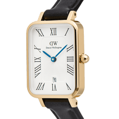 Close-up of the Daniel Wellington Quadro Roman Numerals watch, featuring a rectangular gold case, white dial with a guillochÃ© pattern, blue hands, and a date window.